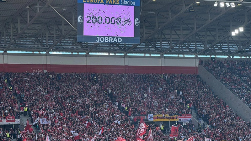 Der Screen im Europa-Park Stadion zeigt an, dass die 200.000 Fahrrad-Fan-Zahl erreicht wurde. Davor sieht man Spieler auf dem Spielfeld.